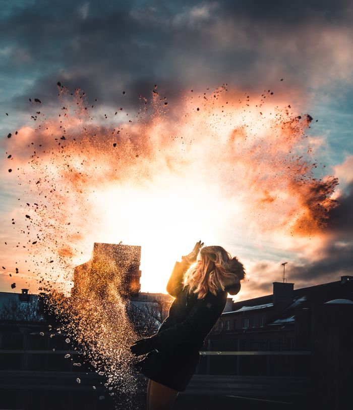A silhouette of a woman with a dramatic sunset and splash effect in the background. Tallinn cityscape visible.